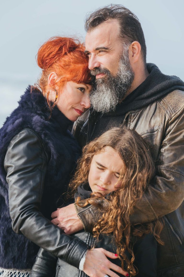 Un homme et une femme, apparemment âmes sœurs, serrent une fille dans leurs bras.