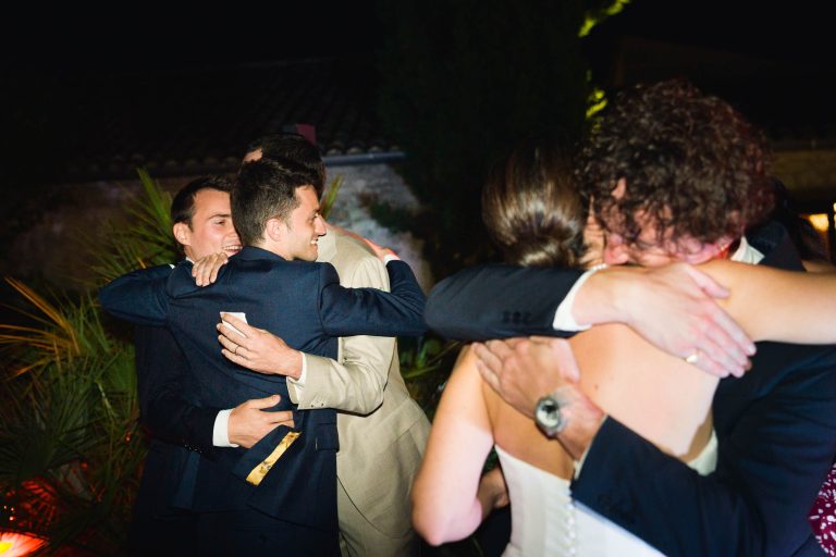 Un groupe de personnes, dont Valentine et Antonin, se serrent chaleureusement dans les bras les uns des autres.