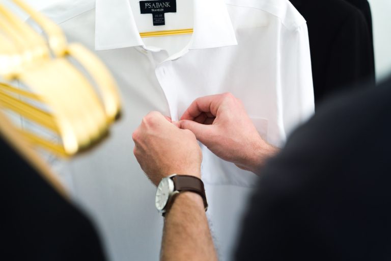 Une personne qui boutonne une chemise blanche.